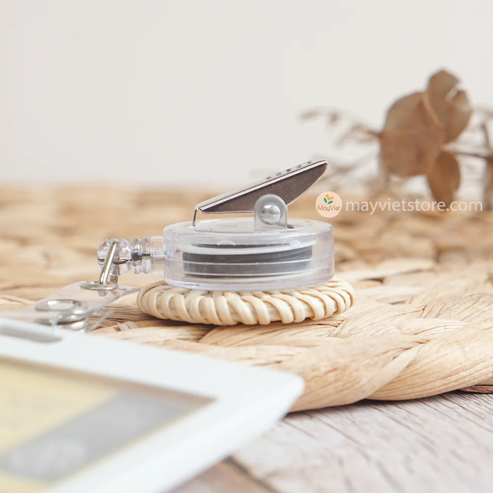 This badge reel clip/card holder is made of rattan. It has a retractable cord and a clip that can be attached to a belt or other clothing. The card holder has three slots for cards, such as a nurse's license and identification card.