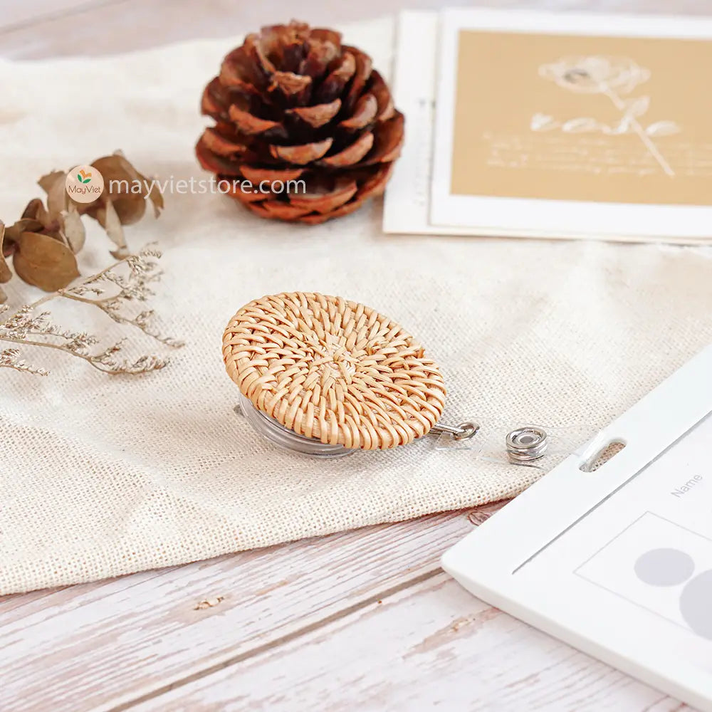 This badge reel clip/card holder is made of rattan. It has a retractable cord and a clip that can be attached to a belt or other clothing. The card holder has three slots for cards, such as a nurse's license and identification card.