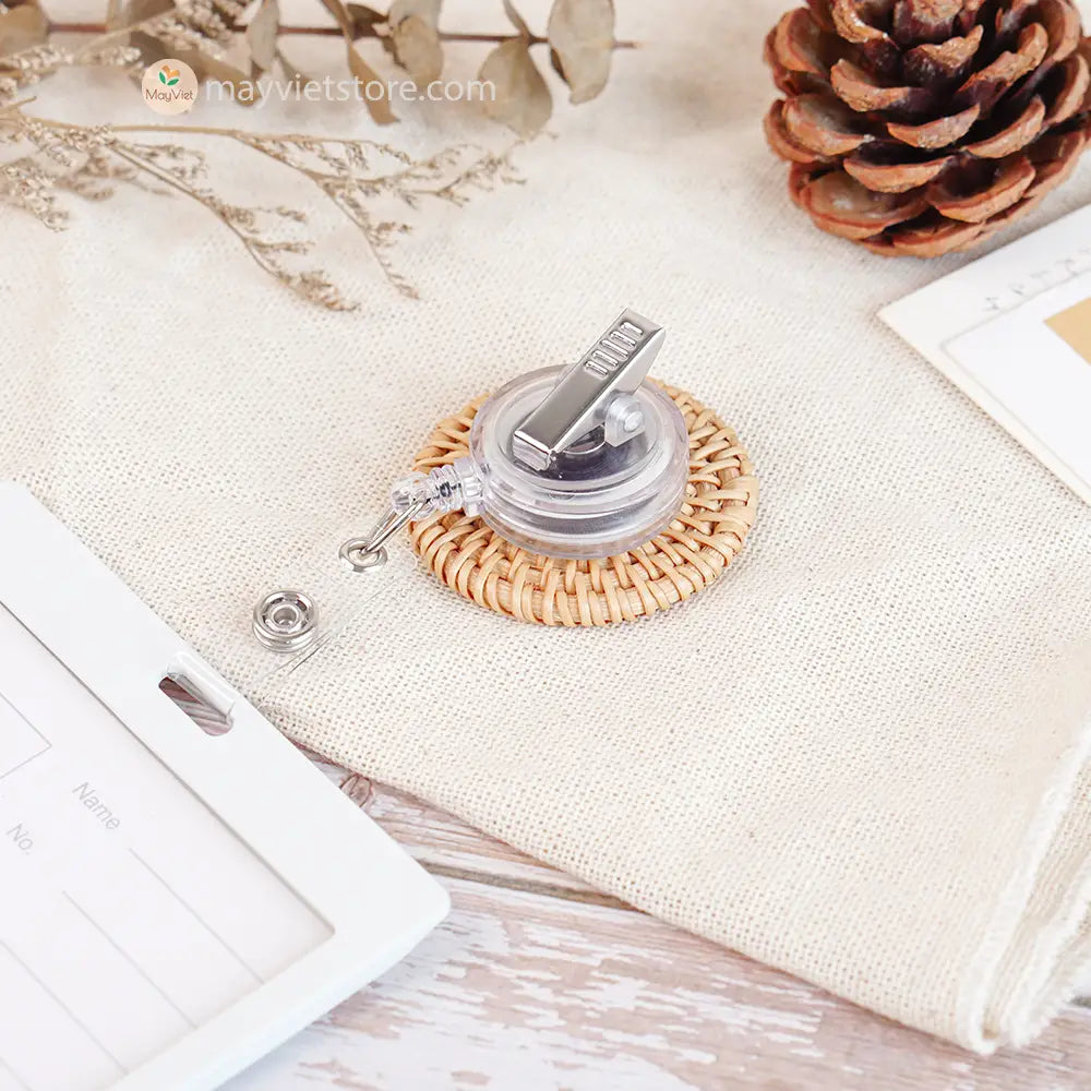 This badge reel clip/card holder is made of rattan. It has a retractable cord and a clip that can be attached to a belt or other clothing. The card holder has three slots for cards, such as a nurse's license and identification card.