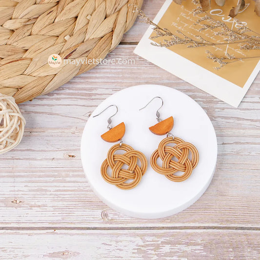 A pair of handcrafted rattan charm earrings with orange wooden beads, made by Mayvietstore. The earrings are made of high-quality rattan and wood, and are lightweight and comfortable to wear. The rattan charms add a touch of fun and personality to the earrings, while the orange wooden beads add a pop of color. These earrings are perfect for any occasion, from a casual day out to a special event.