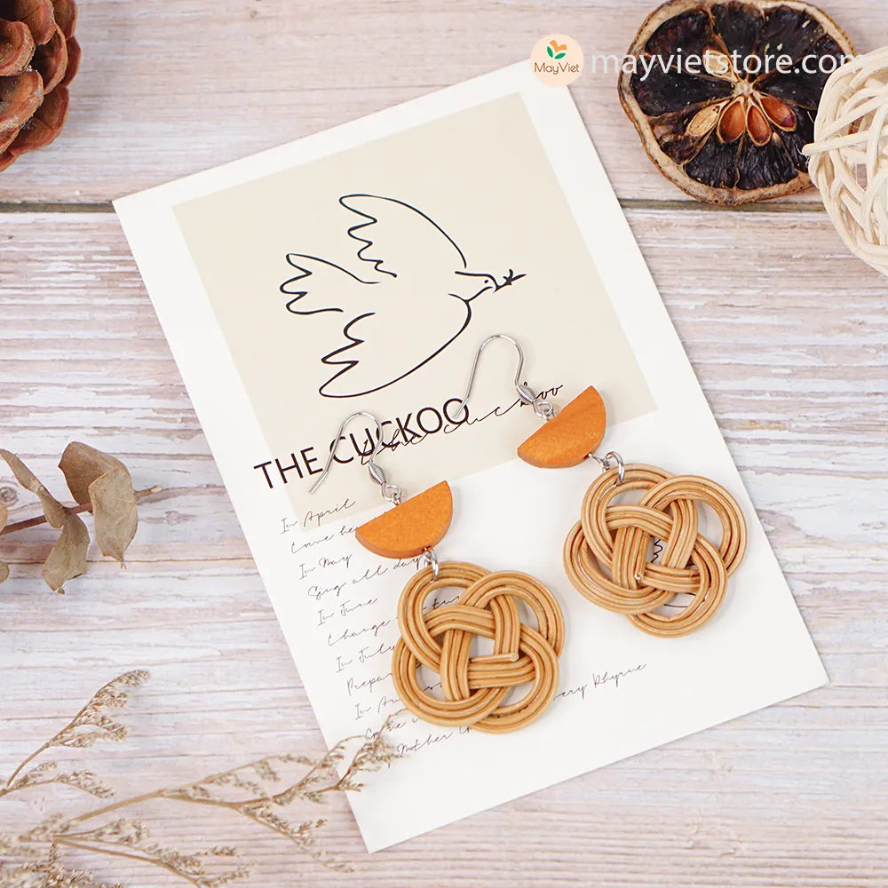 A pair of handcrafted rattan charm earrings with orange wooden beads, made by Mayvietstore. The earrings are made of high-quality rattan and wood, and are lightweight and comfortable to wear. The rattan charms add a touch of fun and personality to the earrings, while the orange wooden beads add a pop of color. These earrings are perfect for any occasion, from a casual day out to a special event.