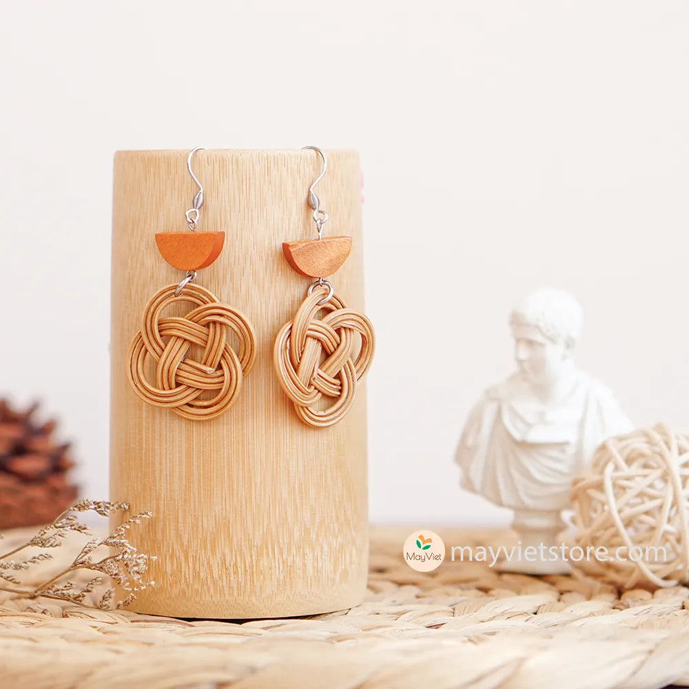 A pair of handcrafted rattan charm earrings with orange wooden beads, made by Mayvietstore. The earrings are made of high-quality rattan and wood, and are lightweight and comfortable to wear. The rattan charms add a touch of fun and personality to the earrings, while the orange wooden beads add a pop of color. These earrings are perfect for any occasion, from a casual day out to a special event.