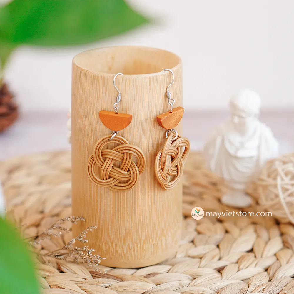 A pair of handcrafted rattan charm earrings with orange wooden beads, made by Mayvietstore. The earrings are made of high-quality rattan and wood, and are lightweight and comfortable to wear. The rattan charms add a touch of fun and personality to the earrings, while the orange wooden beads add a pop of color. These earrings are perfect for any occasion, from a casual day out to a special event.