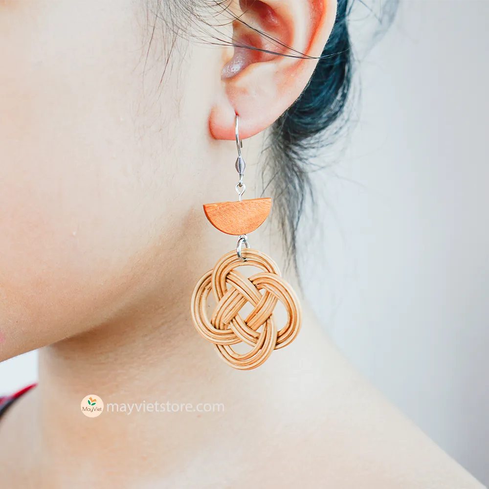 A pair of handcrafted rattan charm earrings with orange wooden beads, made by Mayvietstore. The earrings are made of high-quality rattan and wood, and are lightweight and comfortable to wear. The rattan charms add a touch of fun and personality to the earrings, while the orange wooden beads add a pop of color. These earrings are perfect for any occasion, from a casual day out to a special event.
