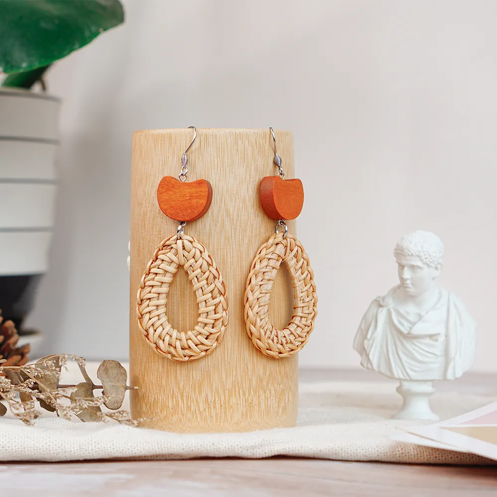 A pair of handcrafted rattan earrings with teardrop-shaped orange wooden beads, made by Mayvietstore. The earrings are made of high-quality rattan and wood, and are lightweight and comfortable to wear. The teardrop-shaped beads add a touch of elegance and sophistication to the earrings, while the rattan gives them a natural and earthy feel. The orange wooden beads add a pop of color and make the earrings stand out. These earrings are perfect for any occasion, from a casual day out to a special event.