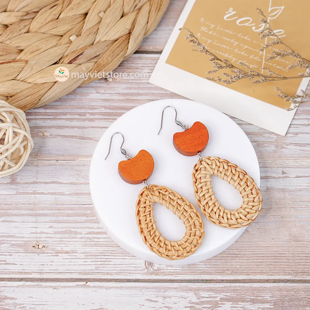 A pair of handcrafted rattan earrings with teardrop-shaped orange wooden beads, made by Mayvietstore. The earrings are made of high-quality rattan and wood, and are lightweight and comfortable to wear. The teardrop-shaped beads add a touch of elegance and sophistication to the earrings, while the rattan gives them a natural and earthy feel. The orange wooden beads add a pop of color and make the earrings stand out. These earrings are perfect for any occasion, from a casual day out to a special event.