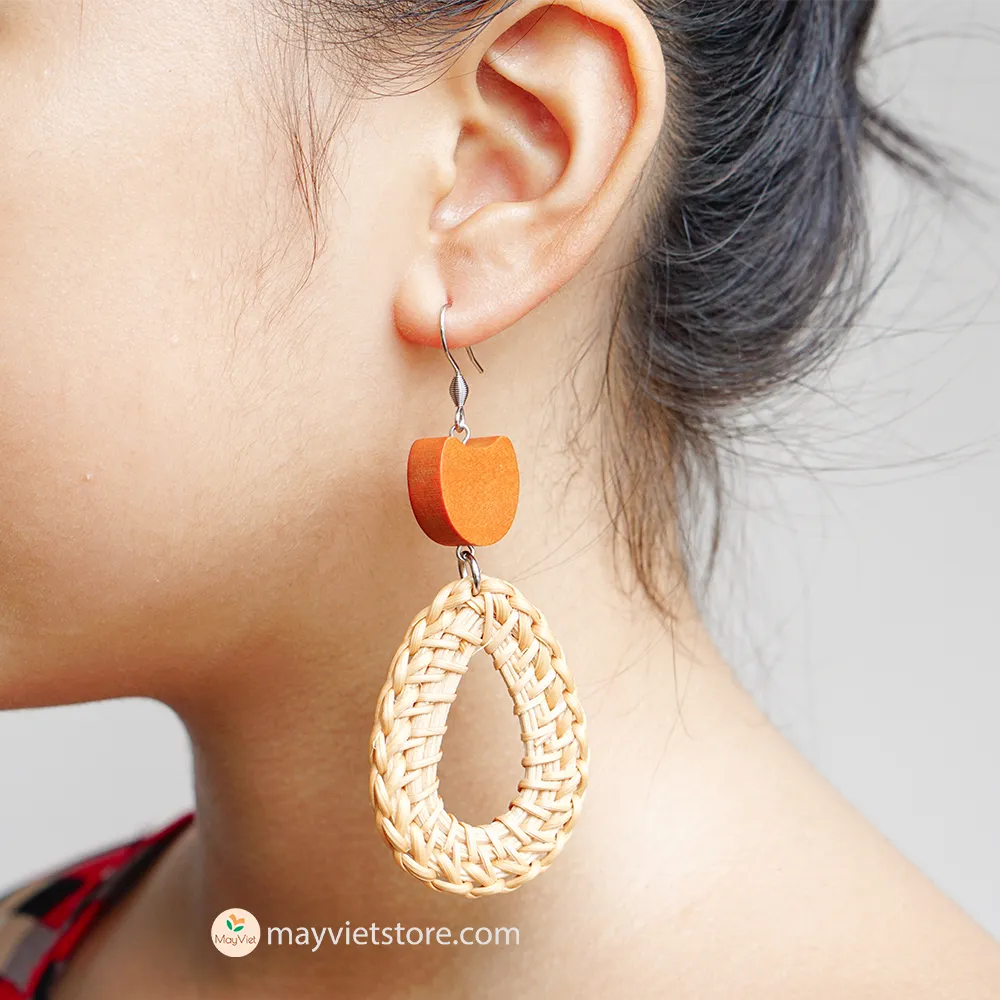 A pair of handcrafted rattan earrings with teardrop-shaped orange wooden beads, made by Mayvietstore. The earrings are made of high-quality rattan and wood, and are lightweight and comfortable to wear. The teardrop-shaped beads add a touch of elegance and sophistication to the earrings, while the rattan gives them a natural and earthy feel. The orange wooden beads add a pop of color and make the earrings stand out. These earrings are perfect for any occasion, from a casual day out to a special event.