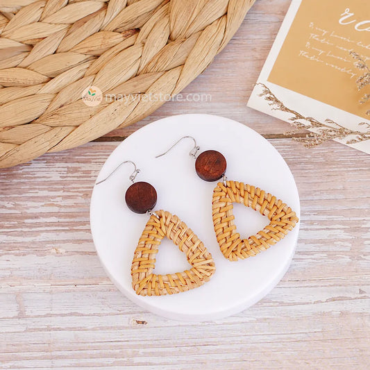 A pair of handcrafted rattan earrings with triangular brown wooden beads, made by Mayvietstore. The earrings are made of high-quality rattan and wood, and are lightweight and comfortable to wear. The triangular beads add a touch of geometric interest to the earrings, and the brown wooden beads give them a warm and natural look. These earrings are perfect for any occasion, from a casual day out to a special event.