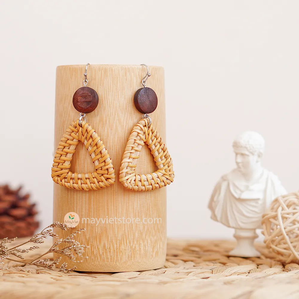A pair of handcrafted rattan earrings with triangular brown wooden beads, made by Mayvietstore. The earrings are made of high-quality rattan and wood, and are lightweight and comfortable to wear. The triangular beads add a touch of geometric interest to the earrings, and the brown wooden beads give them a warm and natural look. These earrings are perfect for any occasion, from a casual day out to a special event.