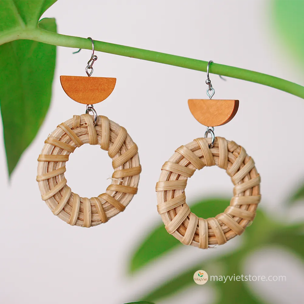 A pair of handcrafted rattan hoop earrings with orange wooden beads, made by Mayvietstore. The earrings are made of high-quality rattan and wood, and are lightweight and comfortable to wear. The rattan hoops are a classic style that is perfect for everyday wear, while the orange wooden beads add a touch of color and personality. These earrings are perfect for any occasion, from a casual day out to a special event.