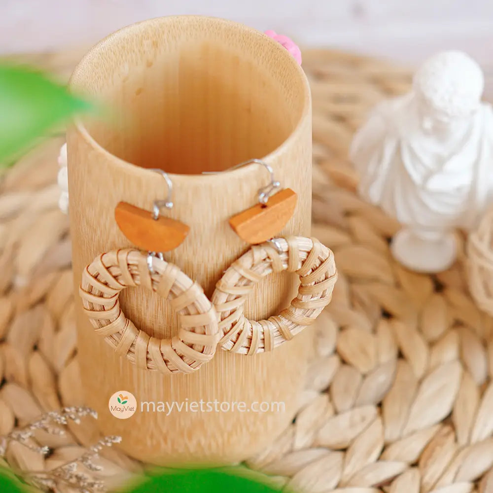 A pair of handcrafted rattan hoop earrings with orange wooden beads, made by Mayvietstore. The earrings are made of high-quality rattan and wood, and are lightweight and comfortable to wear. The rattan hoops are a classic style that is perfect for everyday wear, while the orange wooden beads add a touch of color and personality. These earrings are perfect for any occasion, from a casual day out to a special event.