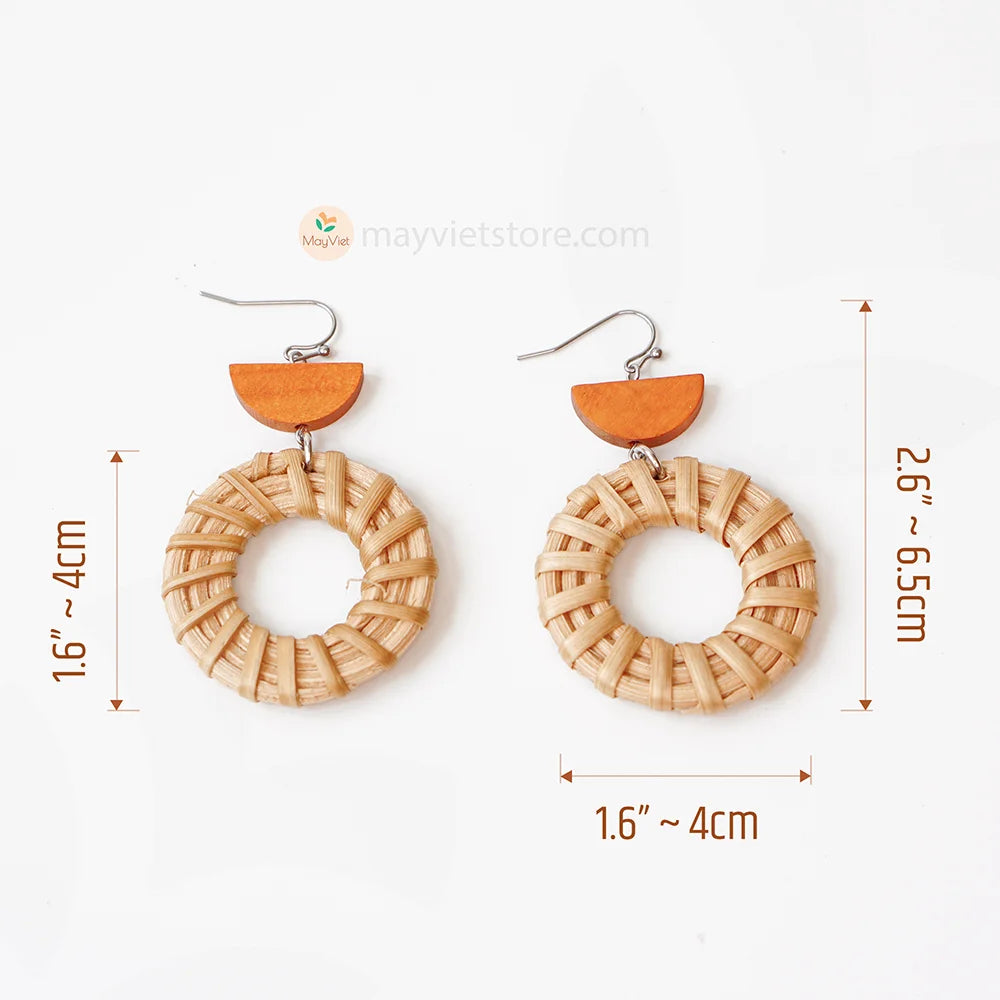 A pair of handcrafted rattan hoop earrings with orange wooden beads, made by Mayvietstore. The earrings are made of high-quality rattan and wood, and are lightweight and comfortable to wear. The rattan hoops are a classic style that is perfect for everyday wear, while the orange wooden beads add a touch of color and personality. These earrings are perfect for any occasion, from a casual day out to a special event.