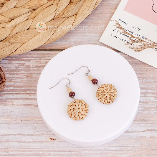 A pair of mini rattan round earrings with wooden beads, handcrafted by Mayvietstore. The earrings are made of high-quality rattan and wood, and are lightweight and comfortable to wear. They are perfect for everyday wear or for special occasions.