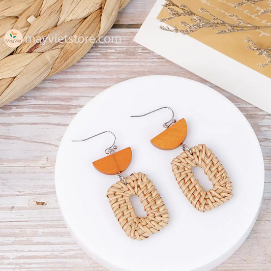 A pair of handcrafted rectangular white rattan earrings with half brown wooden beads, made by Mayvietstore. The earrings are made of high-quality rattan and wood, and are lightweight and comfortable to wear. The rectangular shape adds a touch of sophistication and elegance to the earrings, while the half brown wooden beads add a touch of natural and earthy feel. The contrast between the white rattan and the brown wood beads is eye-catching and unique. These earrings are perfect for any occasion, from a casu