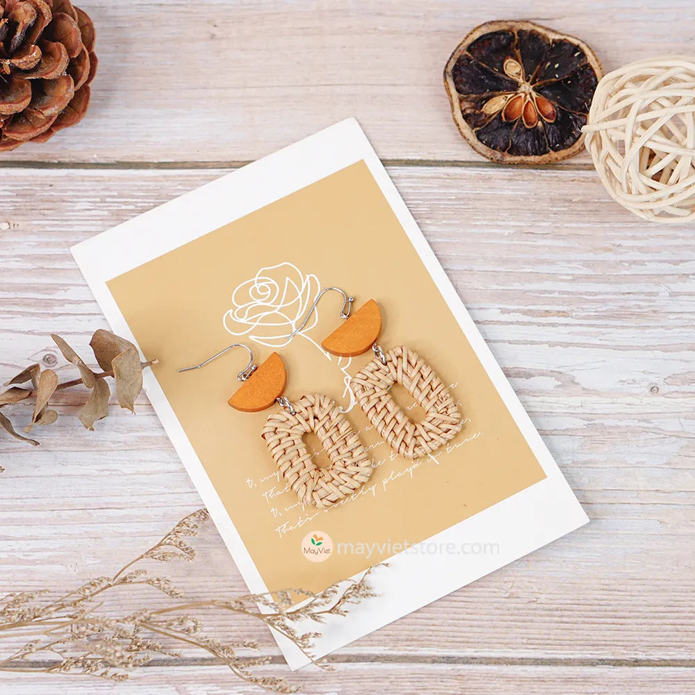 A pair of handcrafted rectangular white rattan earrings with half brown wooden beads, made by Mayvietstore. The earrings are made of high-quality rattan and wood, and are lightweight and comfortable to wear. The rectangular shape adds a touch of sophistication and elegance to the earrings, while the half brown wooden beads add a touch of natural and earthy feel. The contrast between the white rattan and the brown wood beads is eye-catching and unique. These earrings are perfect for any occasion, from a casu
