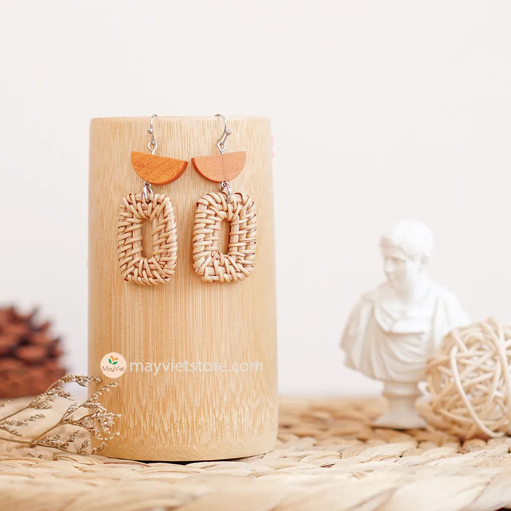 A pair of handcrafted rectangular white rattan earrings with half brown wooden beads, made by Mayvietstore. The earrings are made of high-quality rattan and wood, and are lightweight and comfortable to wear. The rectangular shape adds a touch of sophistication and elegance to the earrings, while the half brown wooden beads add a touch of natural and earthy feel. The contrast between the white rattan and the brown wood beads is eye-catching and unique. These earrings are perfect for any occasion, from a casu