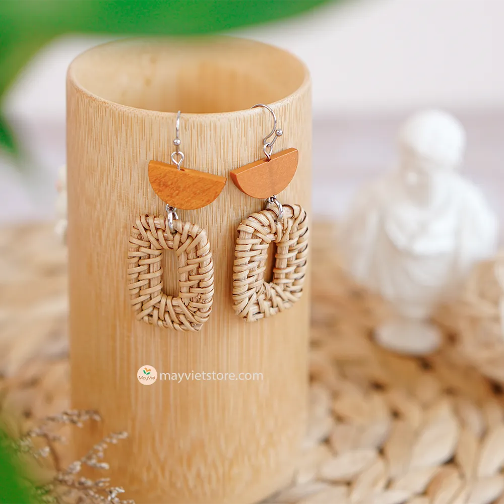 A pair of handcrafted rectangular white rattan earrings with half brown wooden beads, made by Mayvietstore. The earrings are made of high-quality rattan and wood, and are lightweight and comfortable to wear. The rectangular shape adds a touch of sophistication and elegance to the earrings, while the half brown wooden beads add a touch of natural and earthy feel. The contrast between the white rattan and the brown wood beads is eye-catching and unique. These earrings are perfect for any occasion, from a casu