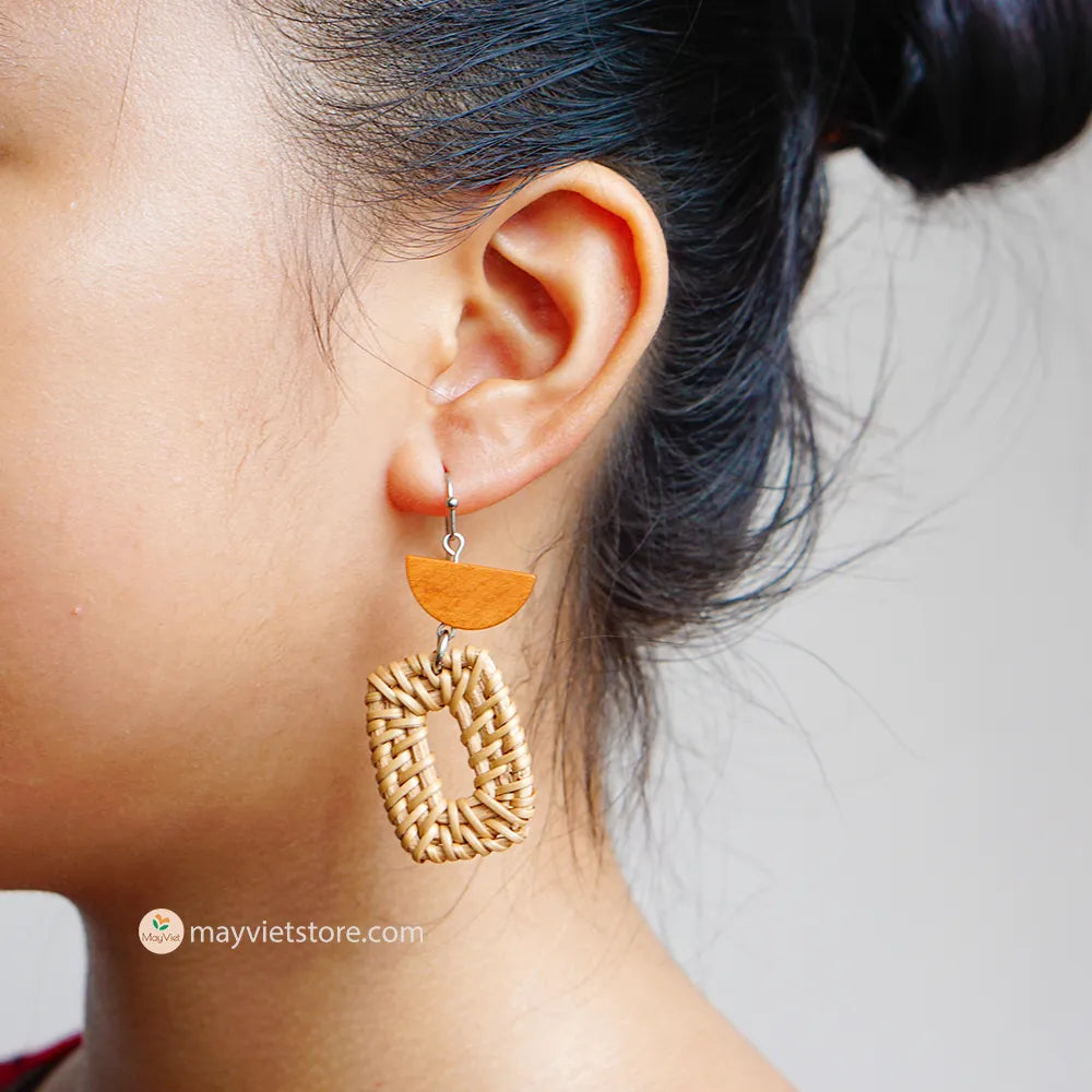 A pair of handcrafted rectangular white rattan earrings with half brown wooden beads, made by Mayvietstore. The earrings are made of high-quality rattan and wood, and are lightweight and comfortable to wear. The rectangular shape adds a touch of sophistication and elegance to the earrings, while the half brown wooden beads add a touch of natural and earthy feel. The contrast between the white rattan and the brown wood beads is eye-catching and unique. These earrings are perfect for any occasion, from a casu