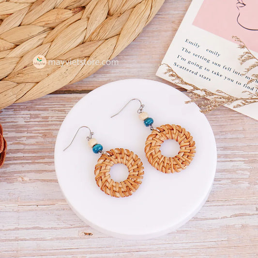 These round rattan hoop earrings with blue and white wooden beads are a fun and stylish accessory. The rattan is lightweight and comfortable to wear, while the blue and white wooden beads add a touch of nautical charm. The hoop shape is classic and versatile, making these earrings perfect for any occasion.