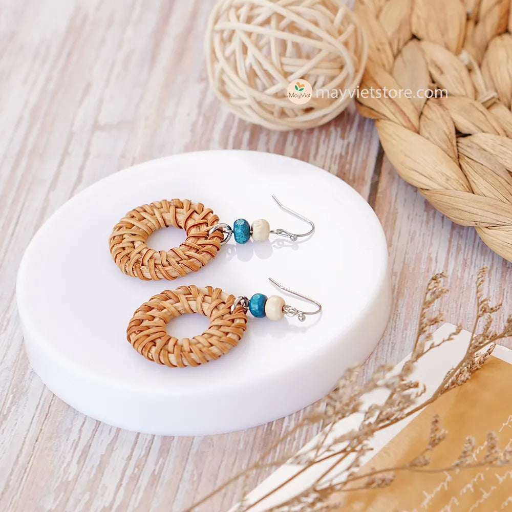 These round rattan hoop earrings with blue and white wooden beads are a fun and stylish accessory. The rattan is lightweight and comfortable to wear, while the blue and white wooden beads add a touch of nautical charm. The hoop shape is classic and versatile, making these earrings perfect for any occasion.