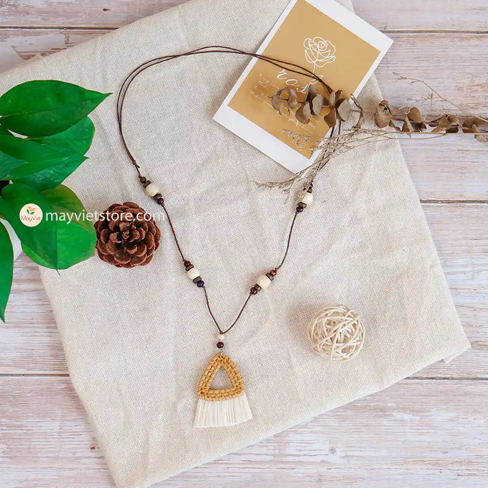 This triangle rattan tassel wooden beads necklace is a unique and stylish accessory. The rattan is lightweight and comfortable to wear, while the wooden beads add a touch of natural beauty. The triangle shape is geometric and modern, while the tassel adds a touch of fun and whimsy. This necklace is perfect for any occasion, from a casual day out to a special event.